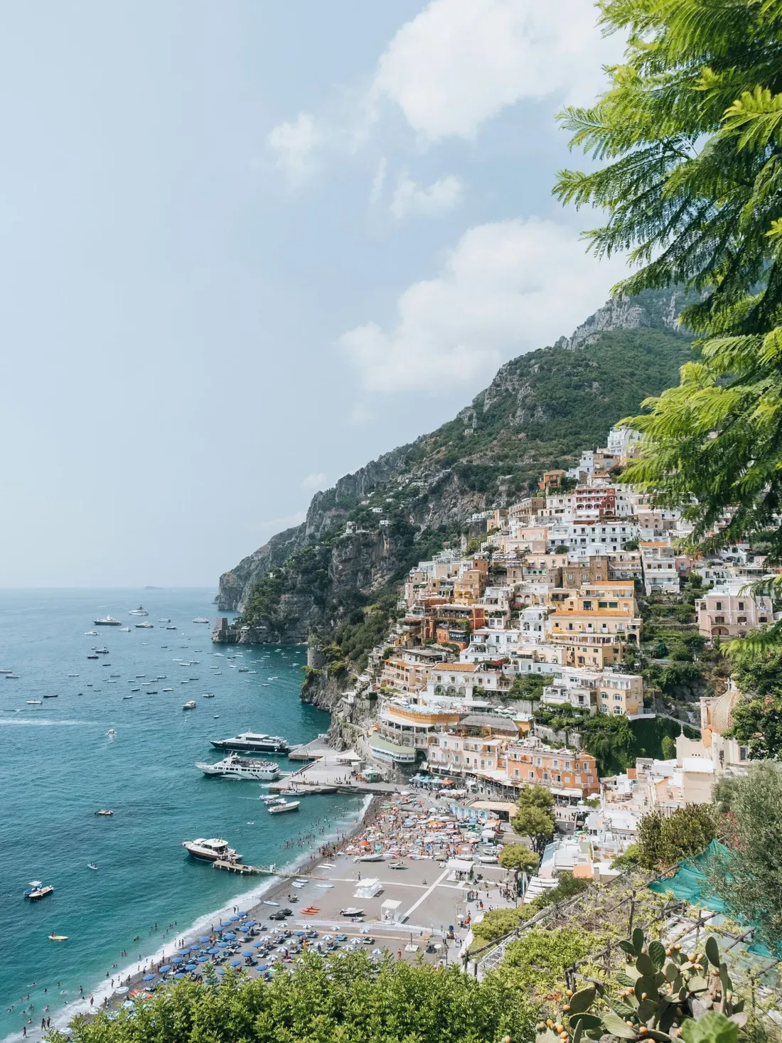 Colorful cliffside Italian village on the Amalfi Coast with boats in the blue sea; a romantic backdrop for tailor-made love dates in Italy.